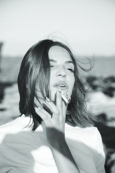 Monochrome portrait of a woman enjoying a cigarette by the ocean in Cyprus.