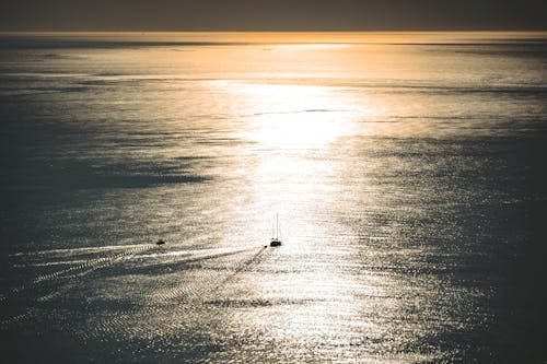 Free Boats Sailing in the Ocean During Golden Hour   Stock Photo