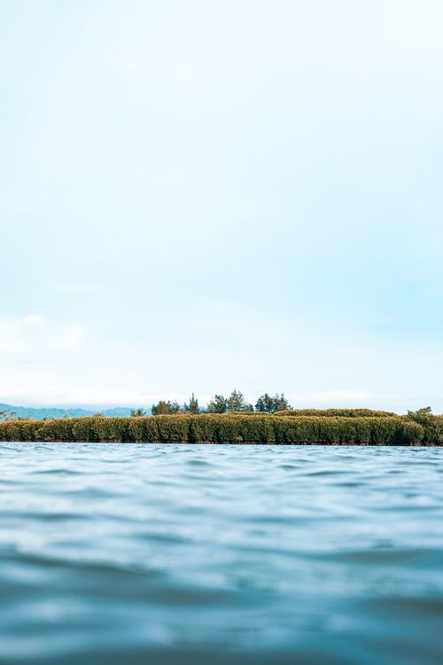 Free Serene view of Indonesian water body with lush green trees under a bright sky. Stock Photo