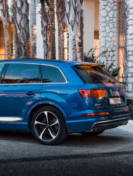 Stylish blue SUV in a modern urban setting with palm trees and illuminated buildings.