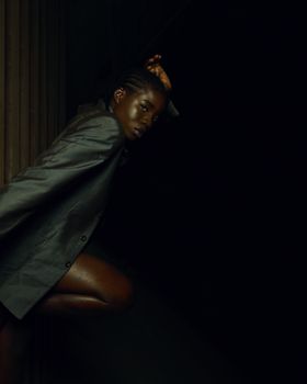 A striking portrait of a woman in a dark blazer posing gracefully against a dark backdrop.