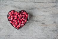 木制桌子上的心形碗里盛着美味多汁的石榴籽