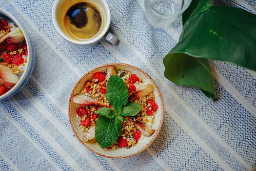 Top-down view of a healthy breakfast bowl with fruits and granola, accompanied by coffee.