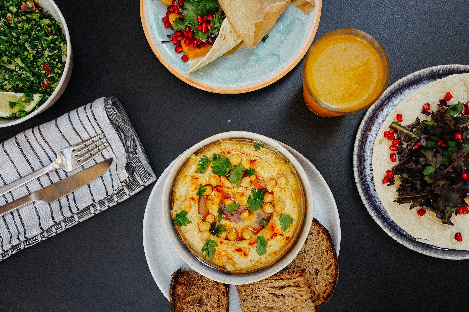 地中海飲食比較:對抗生酮、古飲食、素食與間歇性斷食 A vibrant Mediterranean meal featuring hummus, tabouli salad, bread, and fresh juice, perfect for healthy eating.