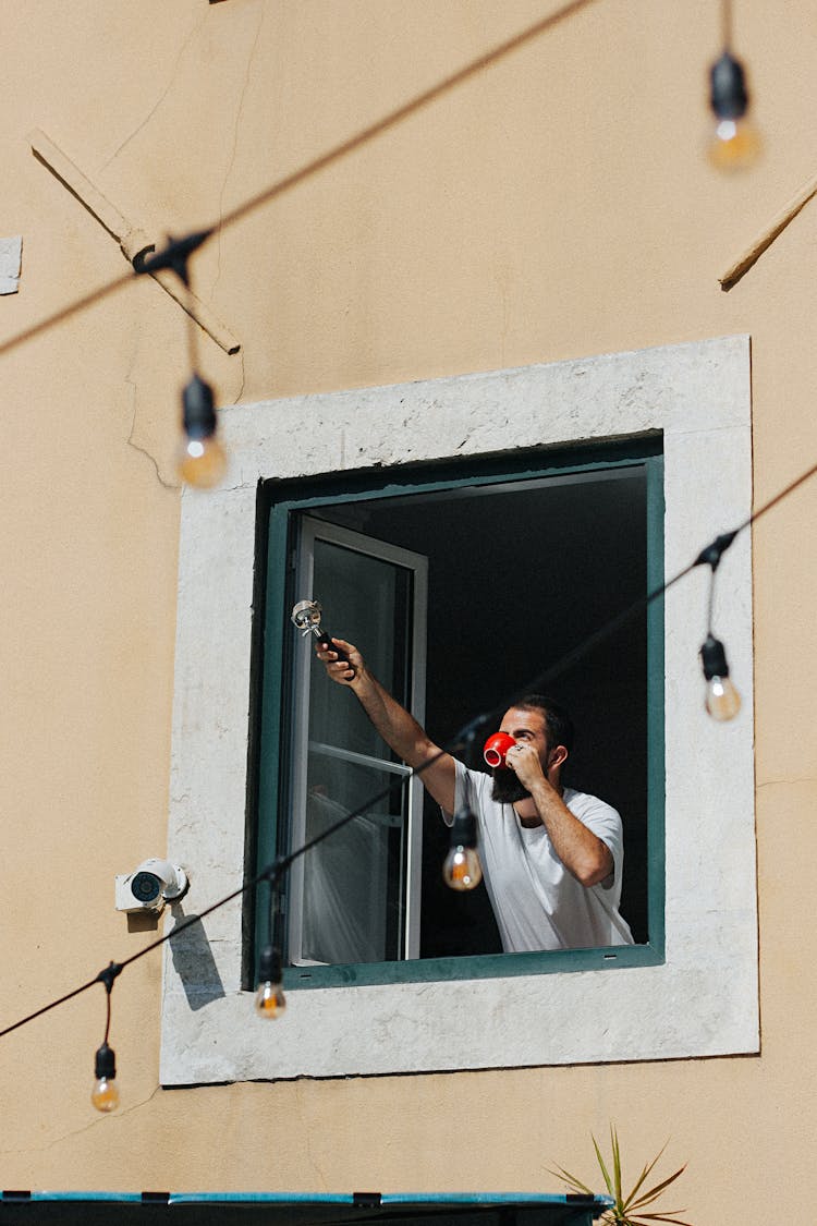 Man Drinking Coffee Behind Window