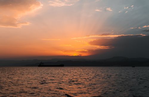 Free A breathtaking sunset over the sea in Jordan with a silhouetted ship and warm colors. Stock Photo