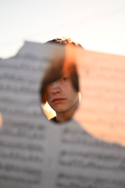 Creative portrait of man seen through a hole in a burned page.