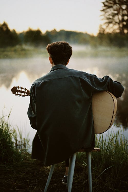 
A Man Playing His Guitar by a Lake