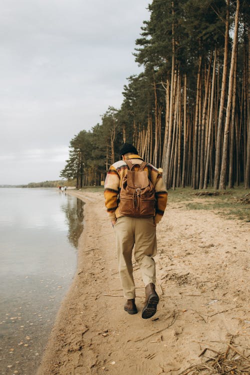 A Man in Plaid Jacket and Brown Pants Standing Near Body of Water