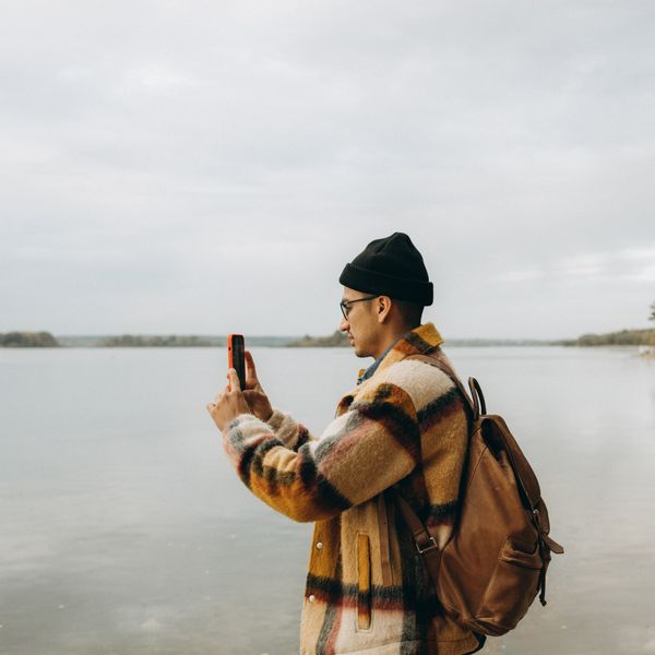 Traveller checking a phone against an open landscape — photo by Maksim Goncharenok on Pexels