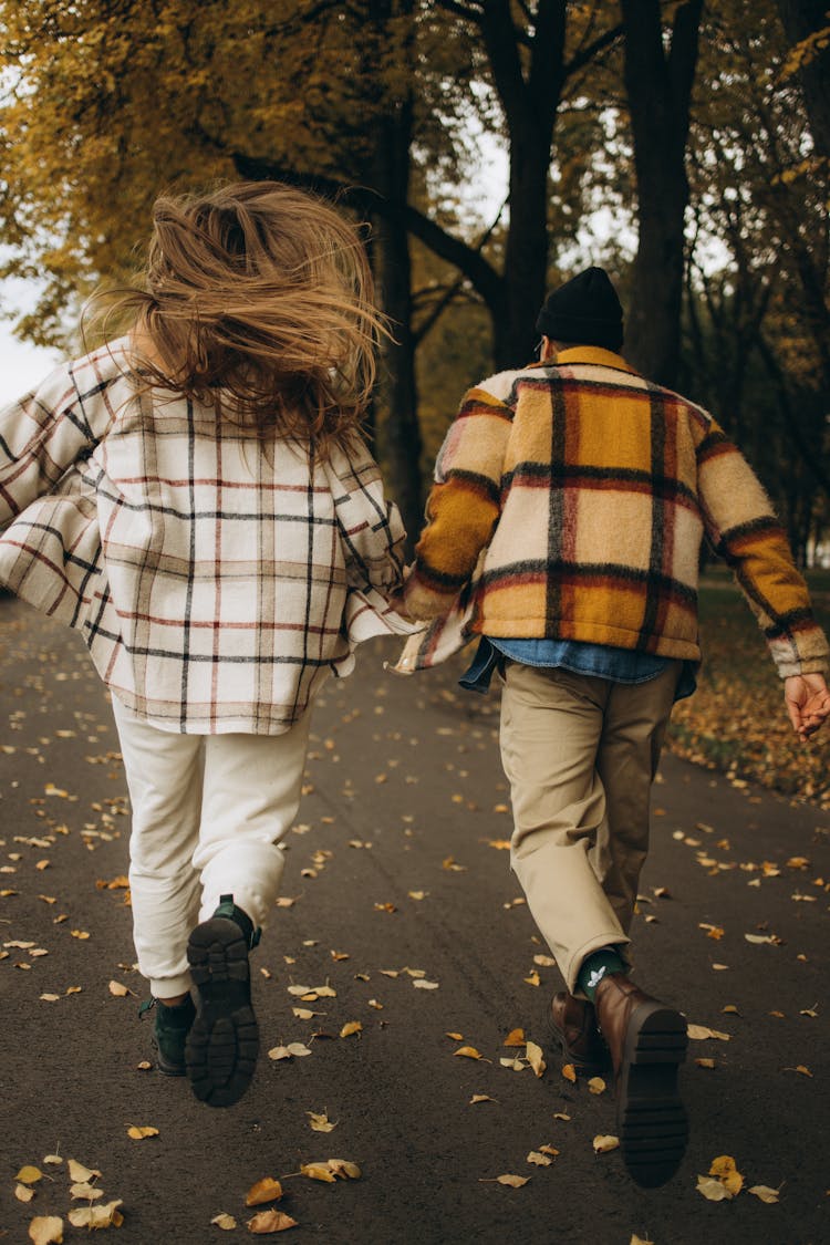 Back View Shot Of A Couple Holding Each Others Hand While Running On A Pathway