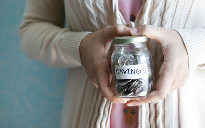 Glass jar labelled savings filled with coins