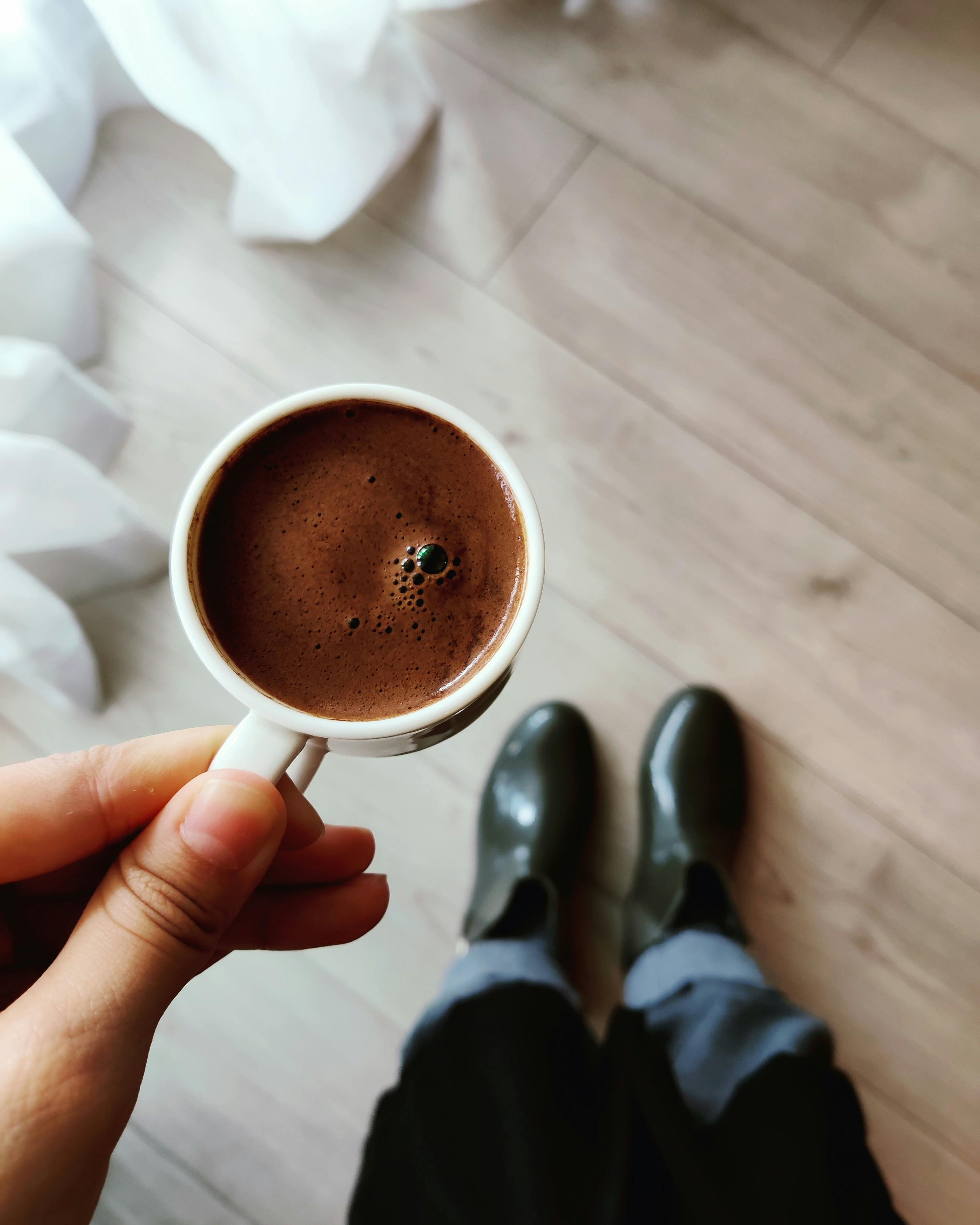 a point of view of a hand holding a cup of coffee