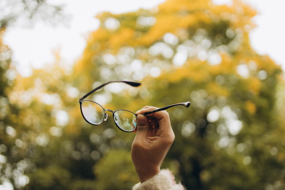 Hand holding eyeglasses outdoors