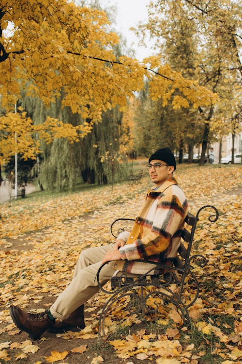 A Man Sitting on a Wooden Bench While Looking Afar