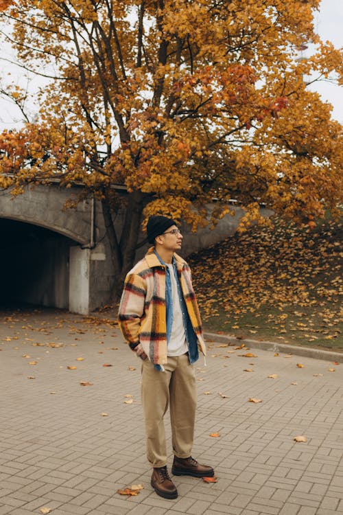 Man Wearing a Checkered Jacket Standing Near a Tree