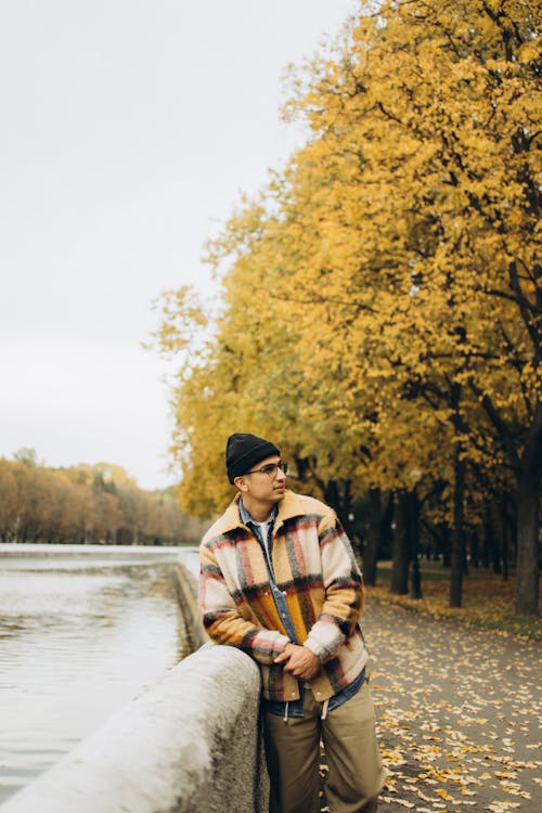 Portrait of a Young Man Leaning on a River Canal Wall in an Autumn Park 