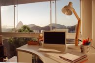 A stylish home office with a laptop, desk lamp, and mountain view through a window.