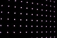 黑色背景上，发光的粉红色点网格构成了一幅充满活力的抽象图案