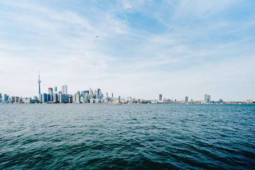 Stunning Toronto skyline view including CN Tower across Lake Ontario under a clear sky.