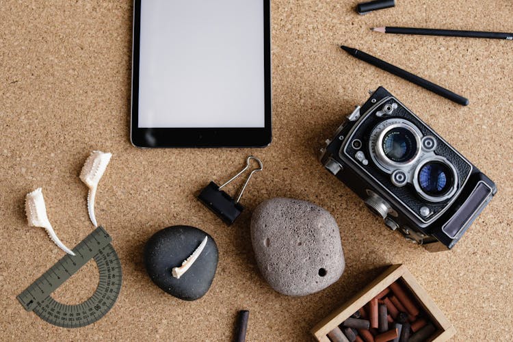 Tablet, Stone, Camera And Items On Desk