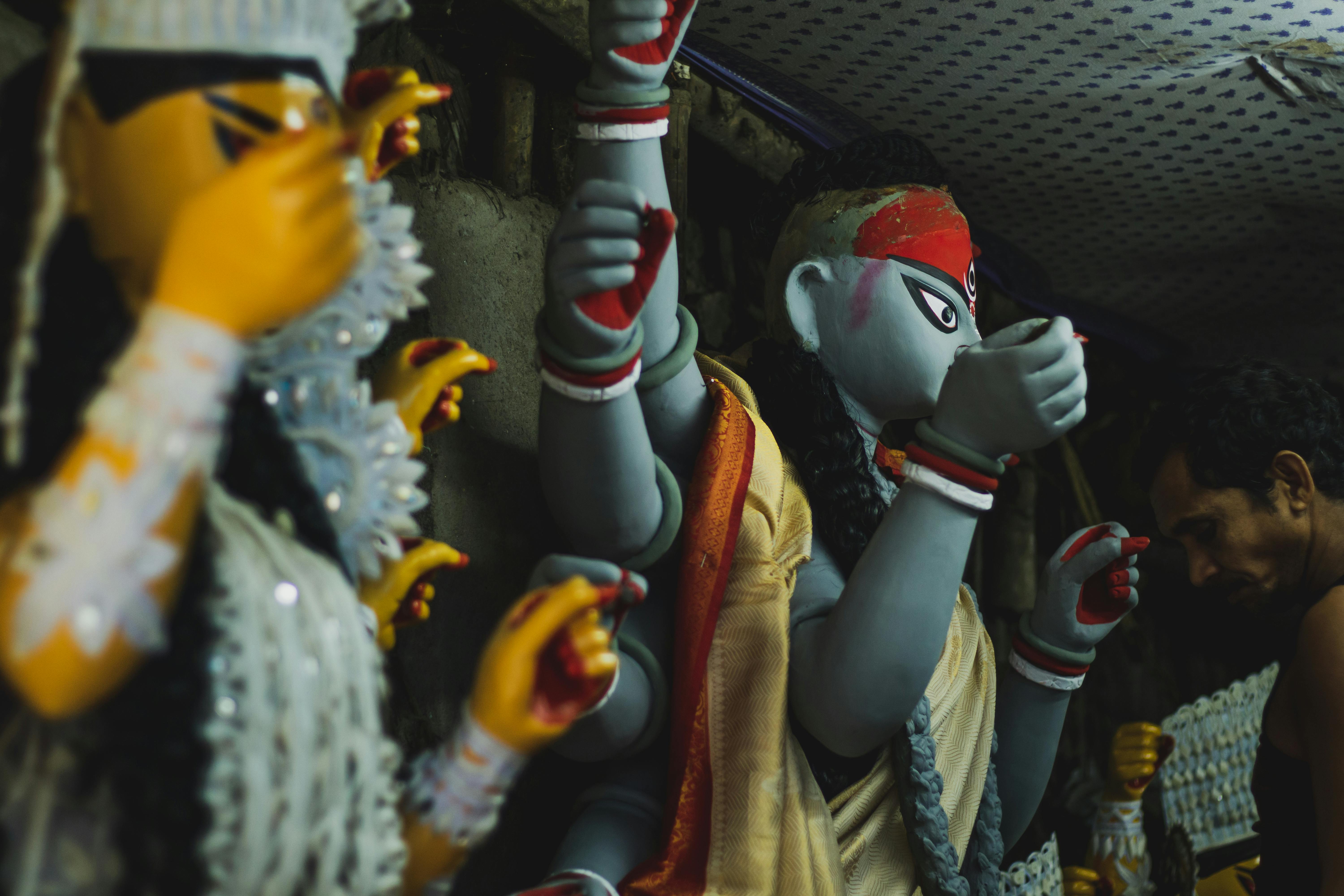 An Indian artisan meticulously crafting traditional Hindu statues in a workshop.