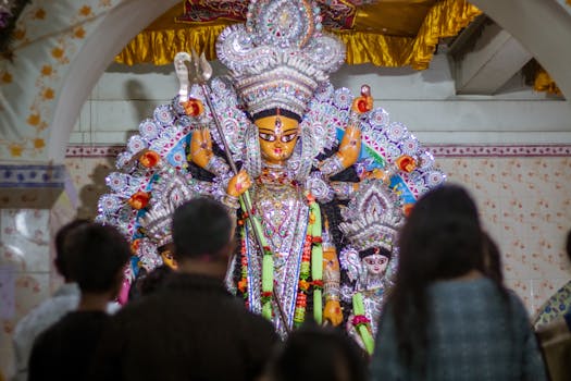 Colorful Durga maa idol worship during an Indian festival with people gathered around.