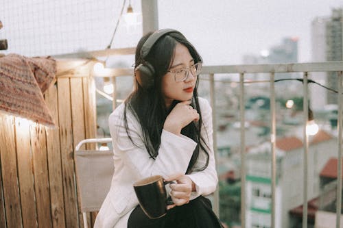 Girl Wearing Headphones Listening to Music on a Balcony