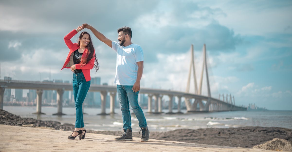 A couple joyously dancing near the iconic Bandra-Worli Sea Link, Mumbai, showcasing love and architecture.