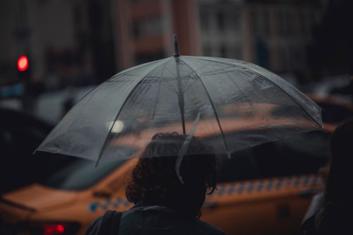 Free A person holding a transparent umbrella on a rainy evening in Istanbul, Turkey, near a taxi. Stock Photo