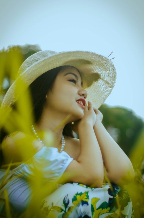 Free Asian woman with pearl necklace and sun hat in a natural outdoor setting. Stock Photo