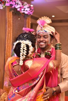A joyous couple embraces during an Indian wedding ceremony, showcasing traditional attire.