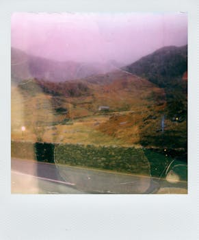 Retro Polaroid photo of a misty hillside in Wales with stone walls, evocative of autumn.