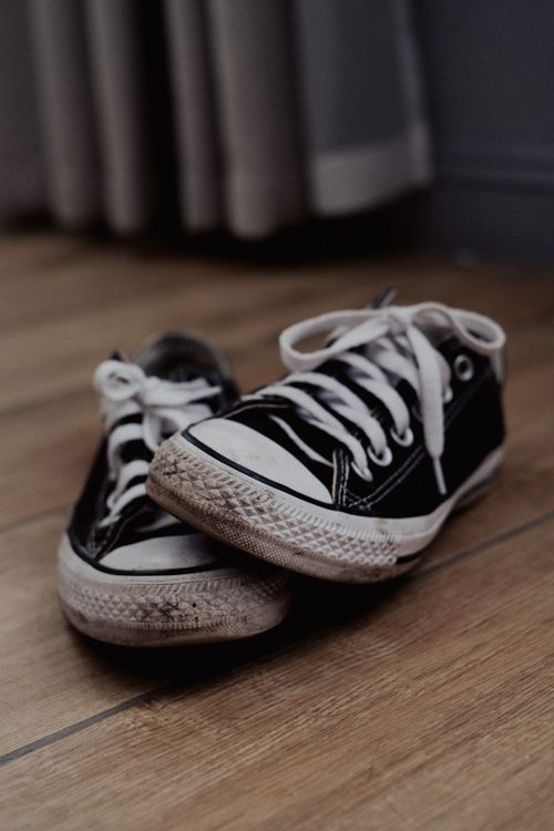 Free Detailed close-up of a pair of black canvas sneakers on a wooden floor indoors. Stock Photo