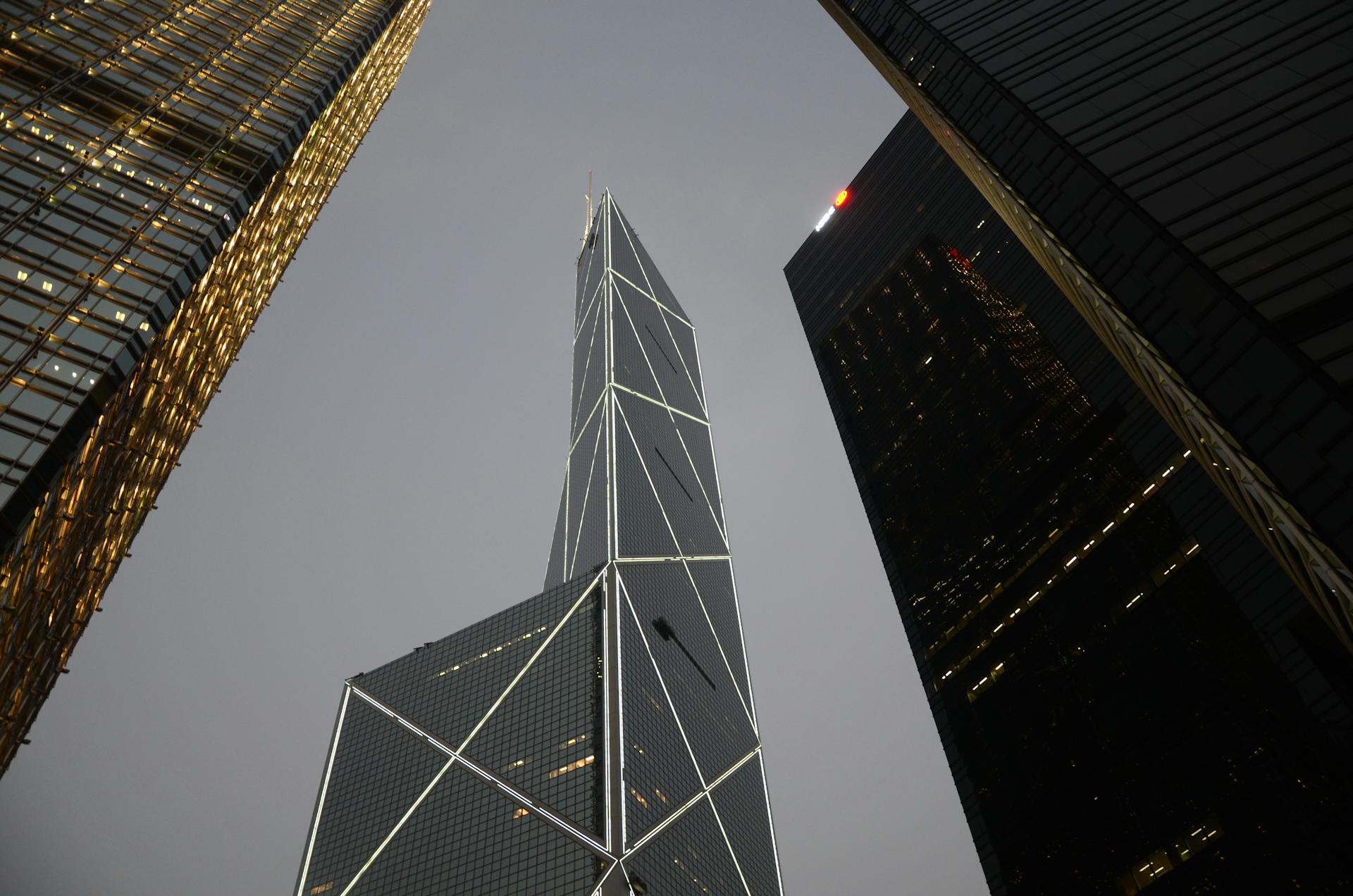 Low angle view of iconic skyscrapers in Hong Kong's financial district under cloudy sky.