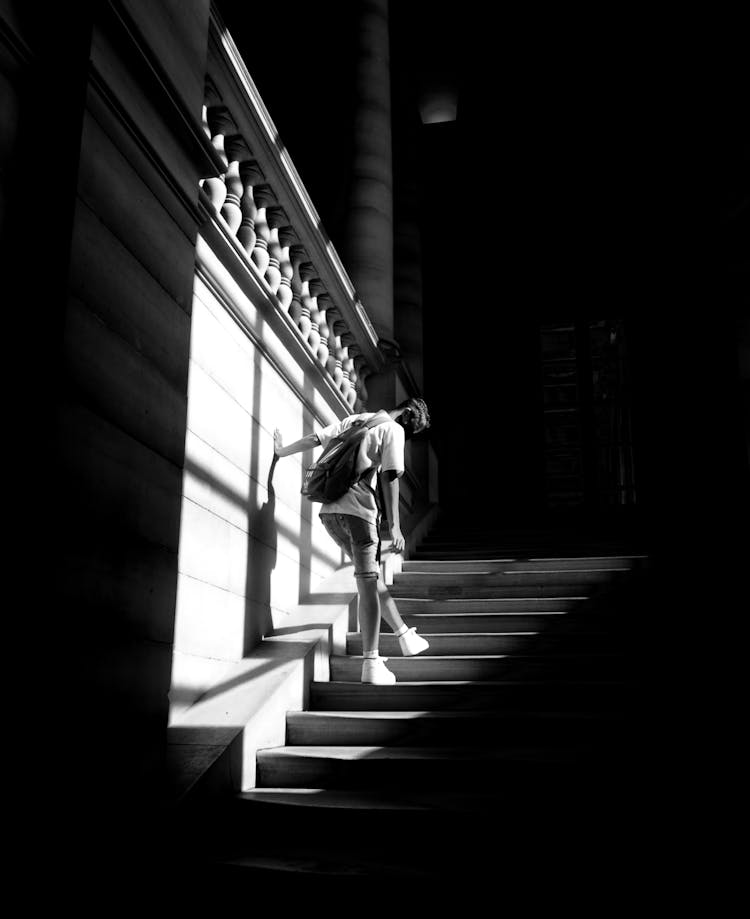 Grayscale Photo Of A Person Going Up The Stairs