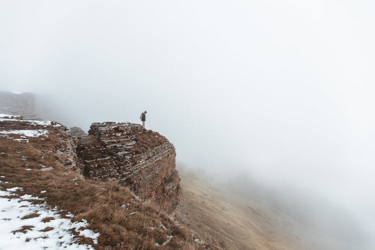 A Person Standing At A Rock Cliff 