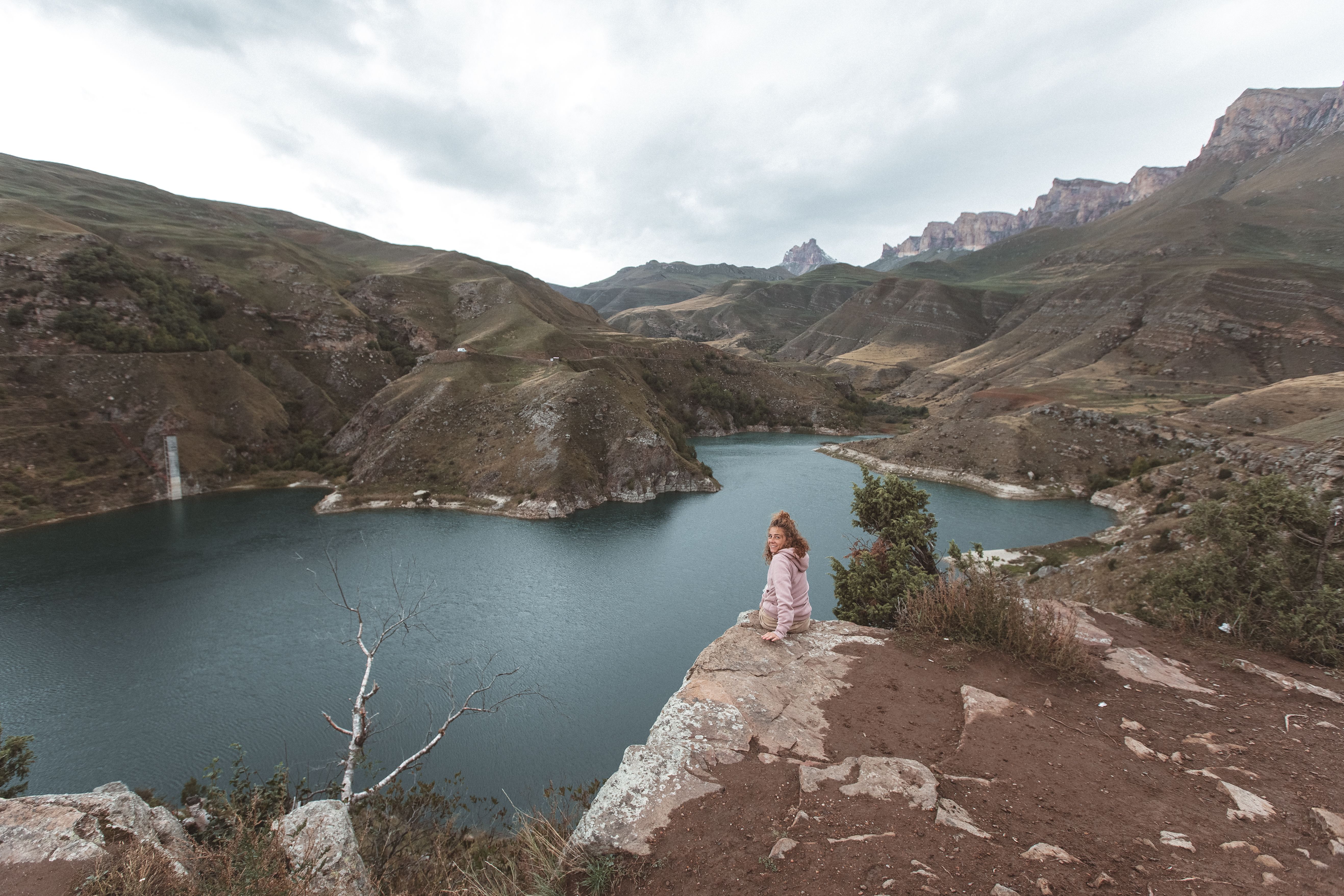 A Female Looking at Camera and Sitting on the Edge of a Rock Cliff ...