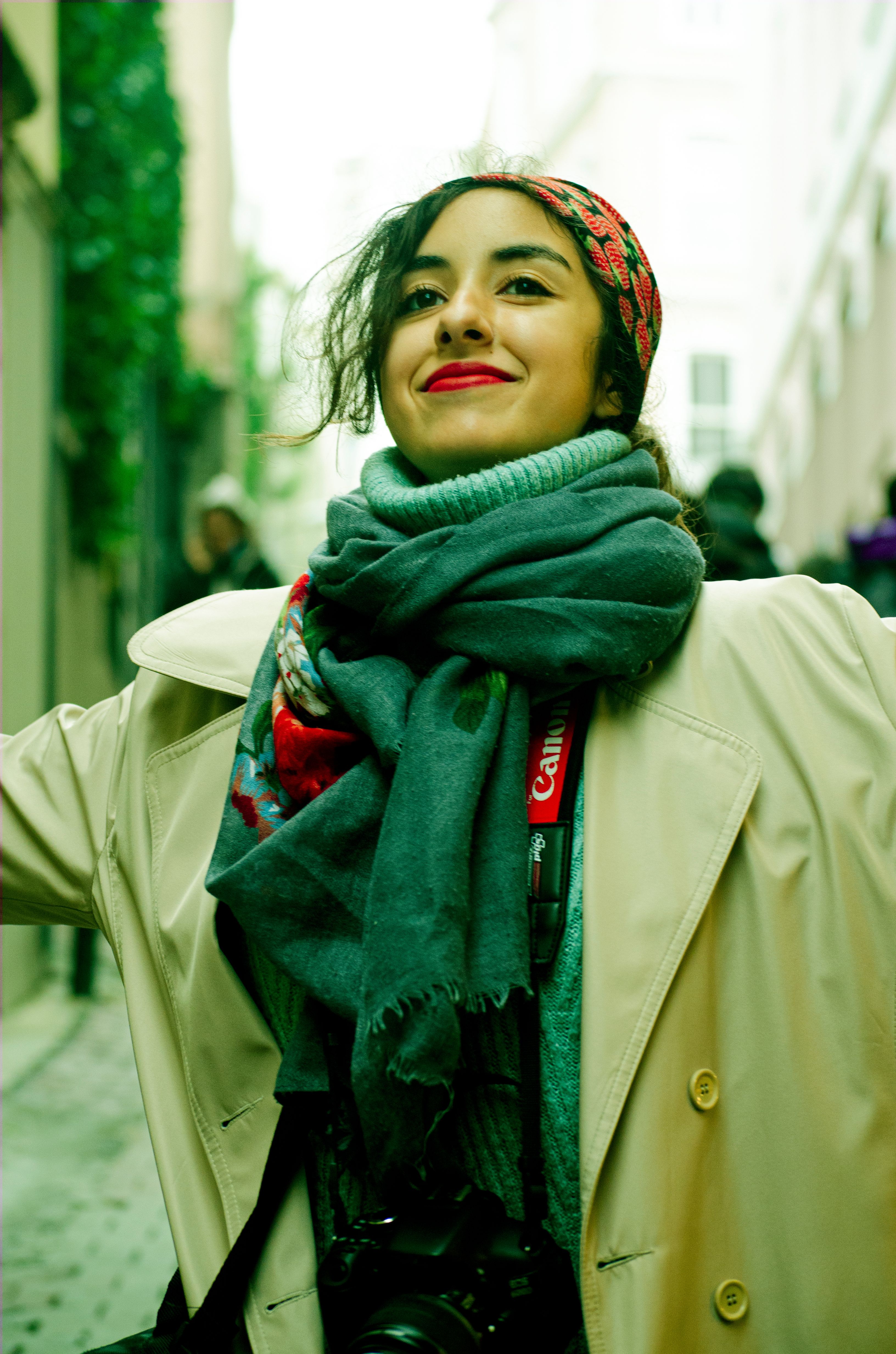Joyful woman in winter clothing with camera, smiling and embracing the moment outdoors.