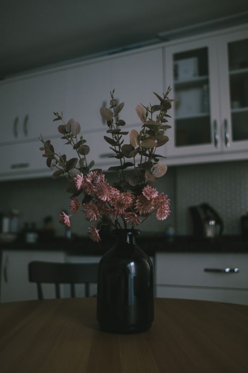 Free Charming pink flowers in a black vase on wooden table, perfect for modern interior design inspiration. Stock Photo