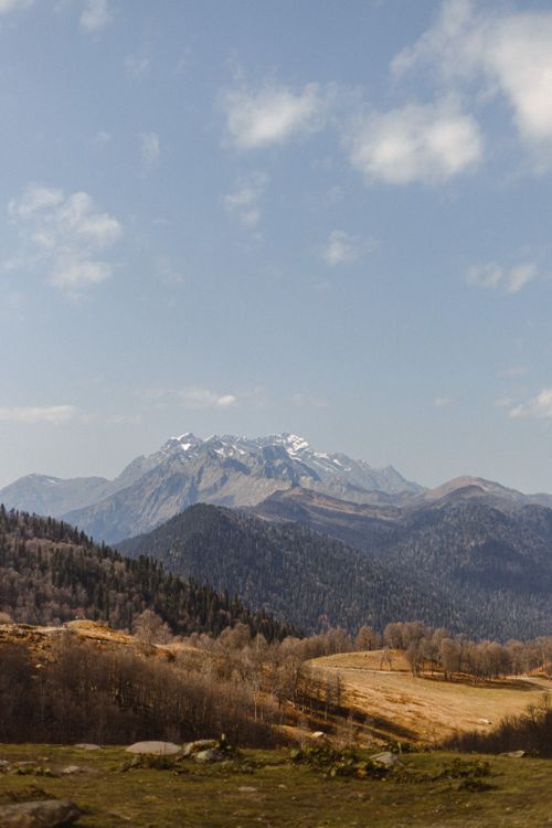 Free Explore the serene beauty of snowcapped mountains and lush forests under a clear blue sky. Stock Photo