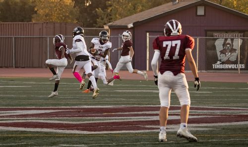 Free Players in action during a high school football game on a field at sunset. Stock Photo