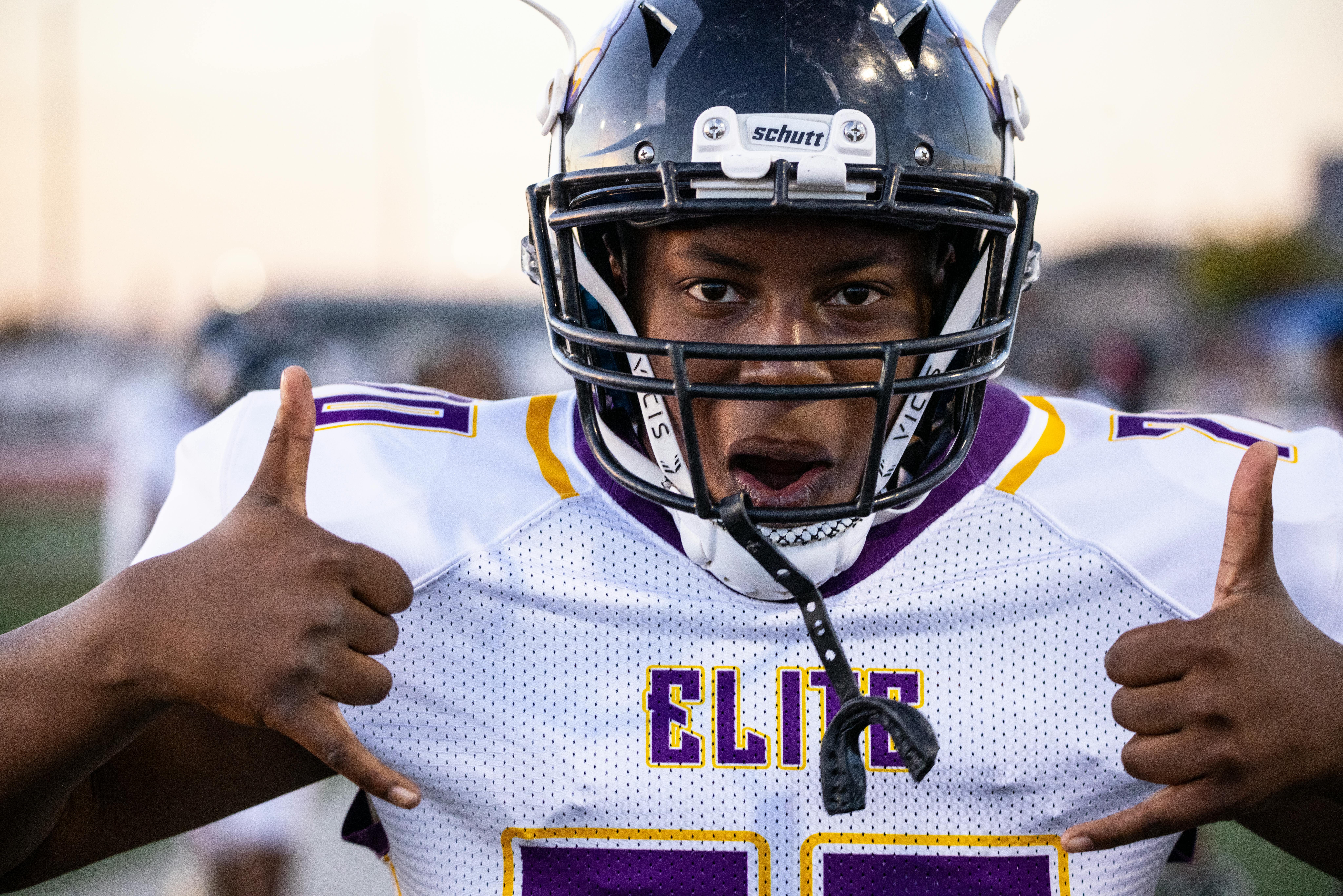 Close-up of a young football player in uniform making a hand gesture on the field.