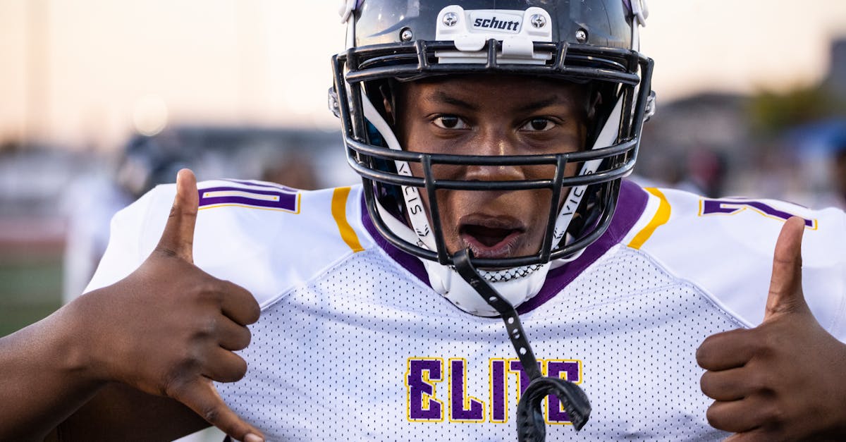 Close-up of a young football player in uniform making a hand gesture on the field.