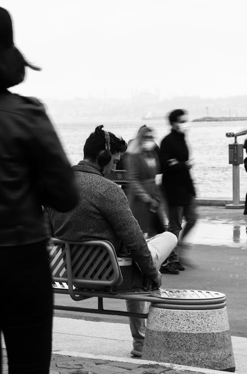 Black and White Photo of Man Sitting on Bench