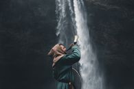 Man in Warrior Clothes Blowing Horn by Waterfall