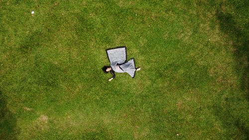Free Drone shot of a woman in a blanket lying on green grass outdoors in Bangladesh. Stock Photo