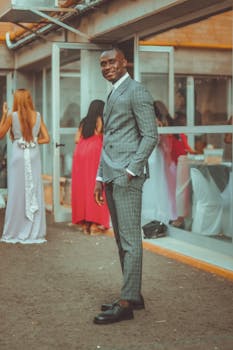Stylish man in a grey checkered suit posing outdoors at a wedding.