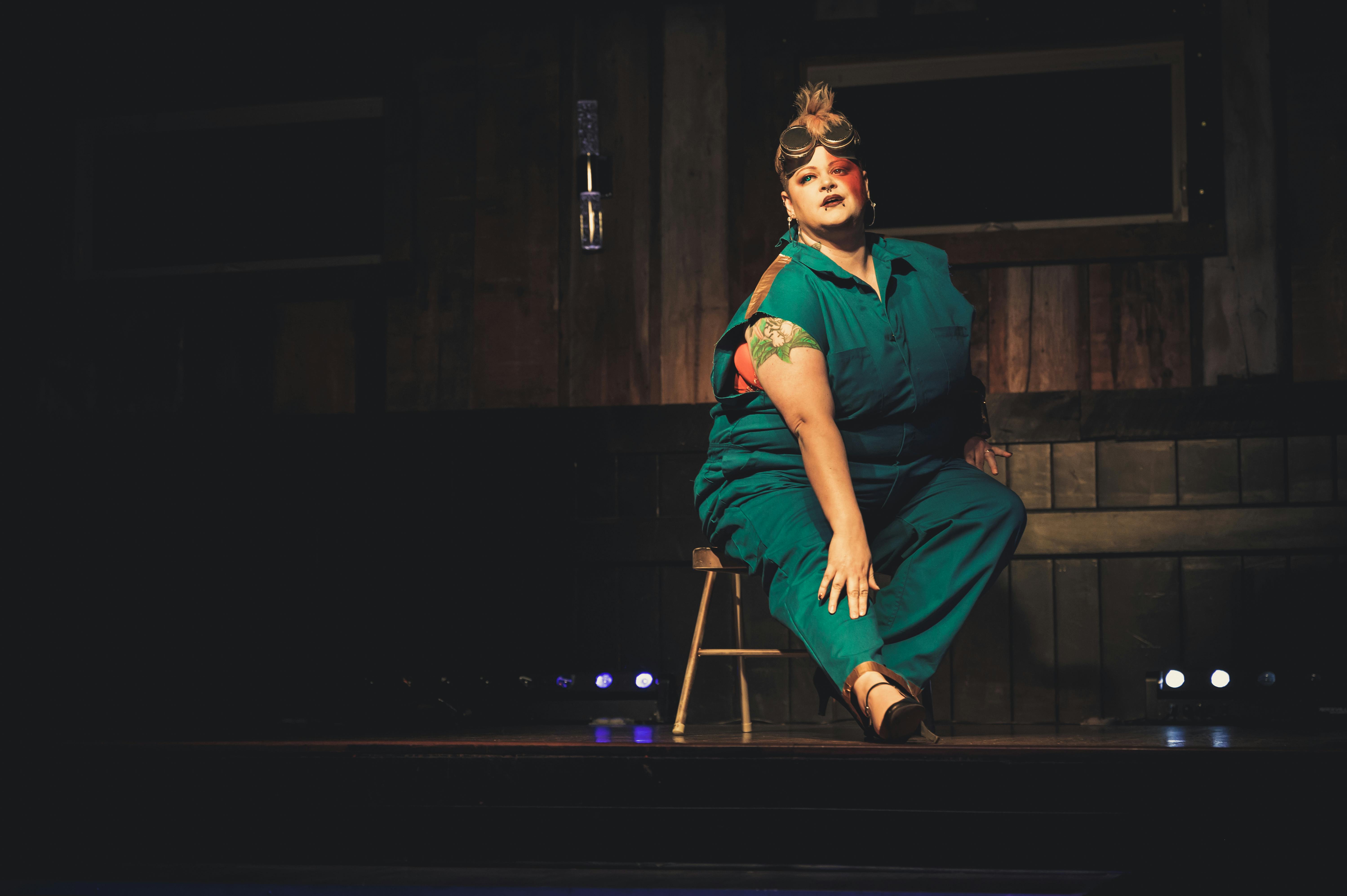 Free A performer in blue attire poses confidently on stage in a dimly lit theatre. Stock Photo