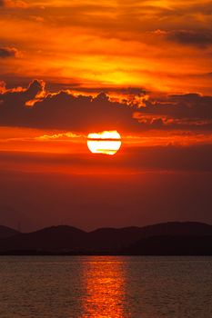 A breathtaking view of the sun setting over a serene sea, casting an orange glow.